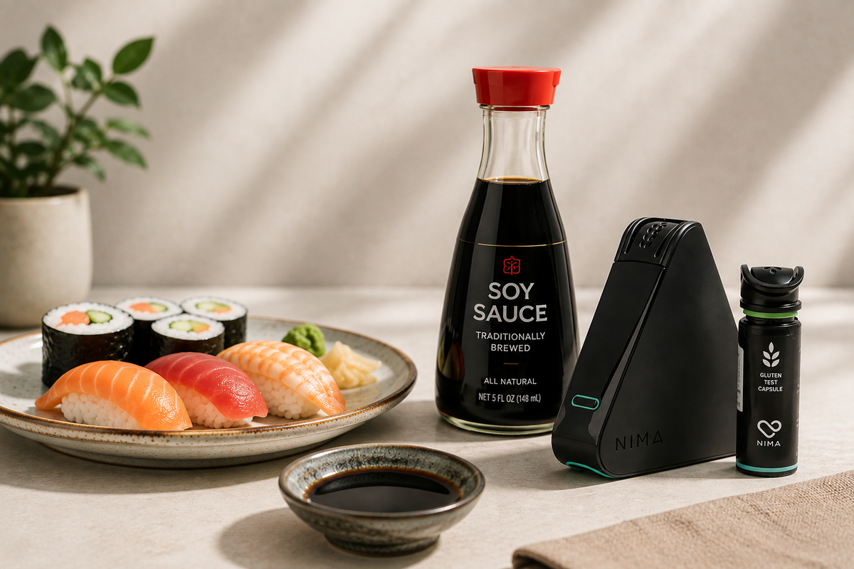 Bottle of soy sauce beside a sushi plate and a NIMA™ gluten sensor, illustrating the question is soy sauce gluten free