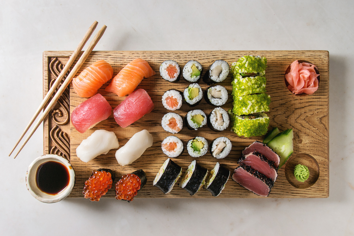 Close-up of assorted sushi rolls on a plate with the NIMA gluten sensor beside them, illustrating the question is sushi gluten free.